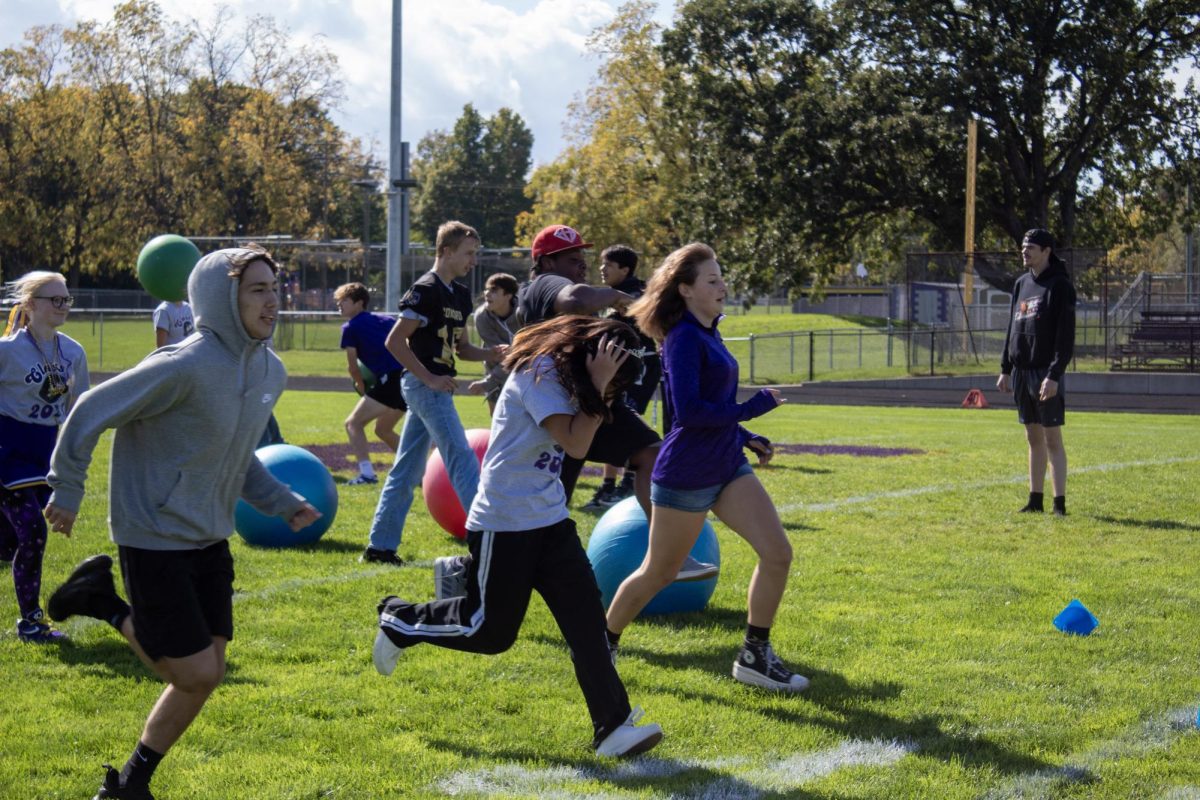 Seniors and freshmen running while trying to avoid the yoga balls in gladiator 