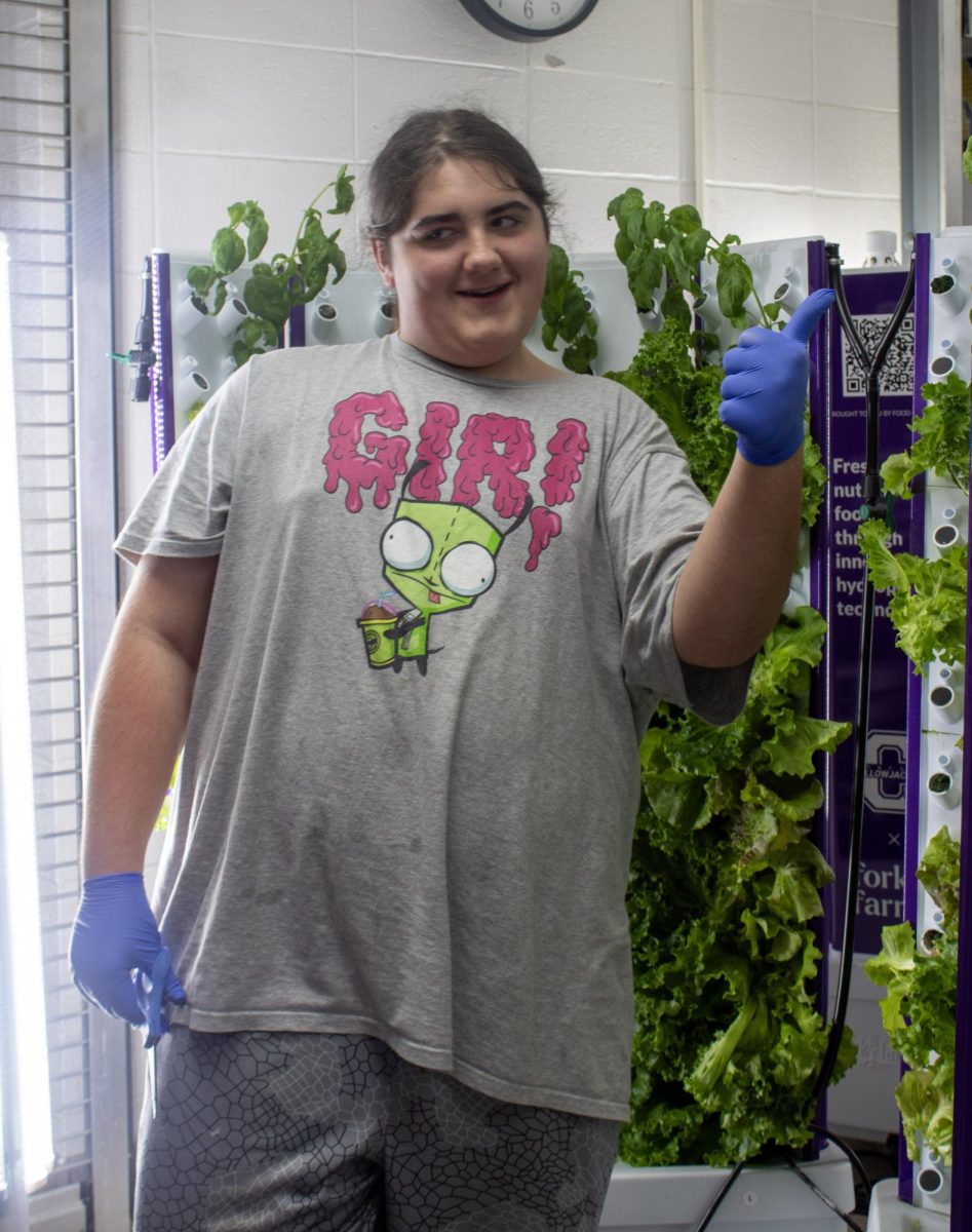 Hayden Stanhope posing in front of lettuce while harvesting.